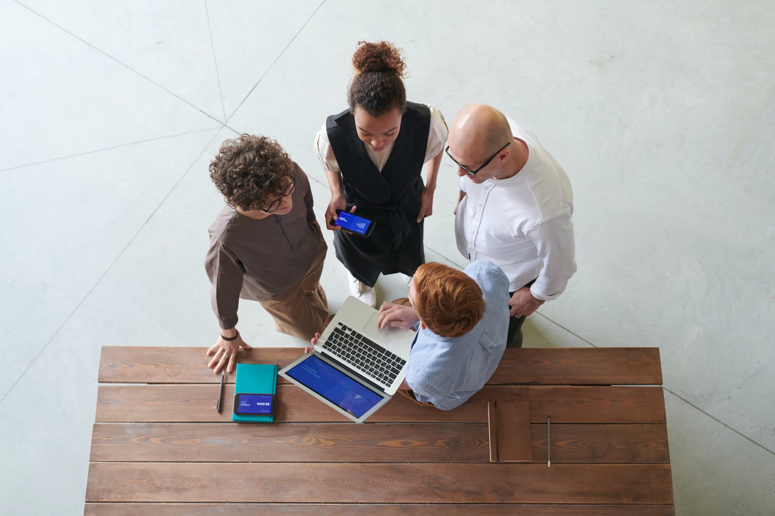 Four people stand and look at a laptop screen