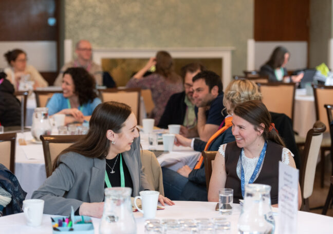 A photo of two people laughing and talking at a networking event