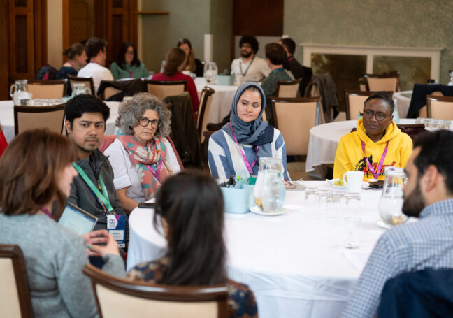 A group of researchers and facilitators sitting around a table participating in a Developing Business-Aware Academics workshop