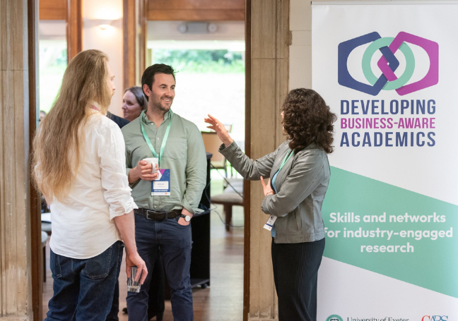A photo of three people standing in front of a DBAA banner, networking